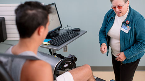 Picture of Motion Analysis Lab staff member testing a research volunteer's leg strength.