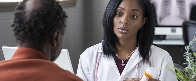 Doctor gesturing to prescription bottle while talking with patient in office