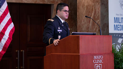 Speaker behind a lectern with Mayo Clinic logo and American flag