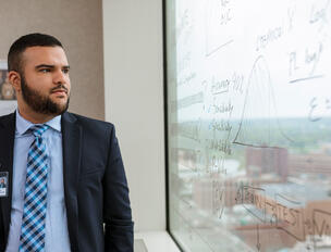 Laboratory member looks at writing on window.