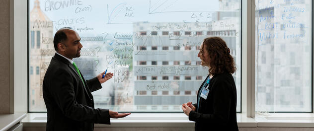 Dr. Athreya and lab member discuss formulas, charts written on window