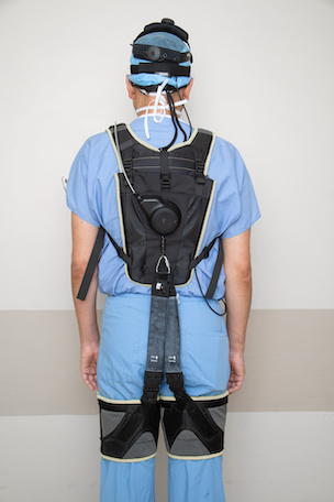 Surgeon in scrubs wearing a back-support exoskeleton