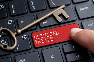 Keyboard with close-up of finger on key labelled CLINICAL TRIALS.