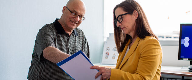 Patient and healthcare professional looking at papers in an exam room