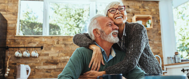 Older couple smiling and hugging in kitchen