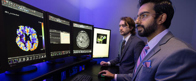 Two researchers looking at brain imaging on computer monitors