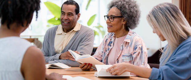 Group of people at a table holding open books